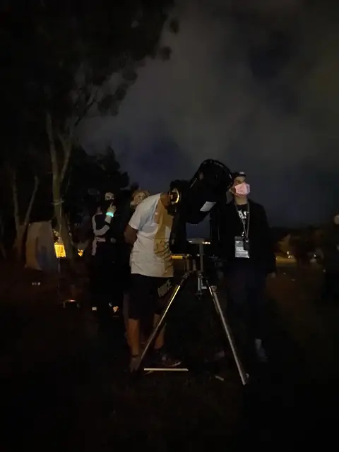 Gece kamp alanında teleskopla gökyüzü gözlemi yapan katılımcılar